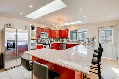 a kitchen with red cabinets and a large kitchen island at Scenic Home with Sauna - 7 Mi to Heavenly Mountain! in Kingsbury