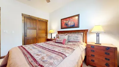 a bedroom with a bed and a dresser and lamp at Woodwinds #1303 condo in Mammoth Lakes