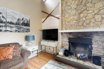 a living room with a fireplace and a tv at Snowy Pines in Fish Camp
