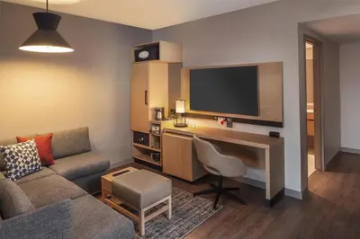 a living room with a couch and a desk with a television at Hyatt Place Reno in Reno
