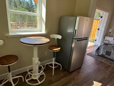 a kitchen with a refrigerator and a table and stools at Ambrosia Hour on the Markleeville River in Markleeville