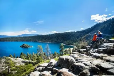two people sitting on top of a mountain overlooking a lake at Marriott Timber Lodge Luxury Studio in Stateline