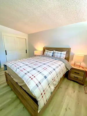 a bedroom with a bed with a plaid comforter and two lamps at NEW cozy beautiful house with pool and hot tub in Fair Oaks