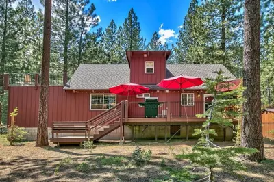 a red house with two red umbrellas on a deck at Tahoe Townie - Cozy Cabin in South Lake Tahoe! in South Lake Tahoe