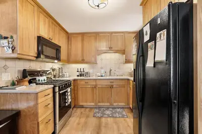 a kitchen with wooden cabinets and a black refrigerator at Moose Haven - Family Favorite! Close to beaches! in South Lake Tahoe