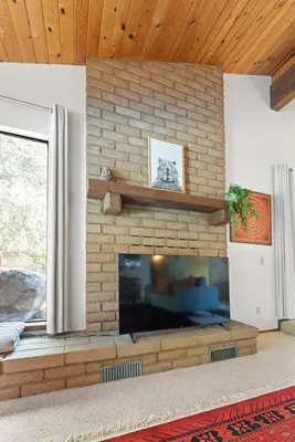 a living room with a large brick fireplace at Sequoia Zen River House in Three Rivers