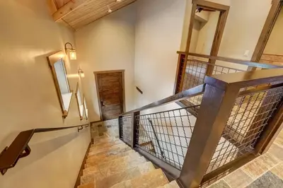 a winding staircase with wooden railings and a wooden door at Chateau de Navahoe - Luxury - Hot tub - Large yard in South Lake Tahoe