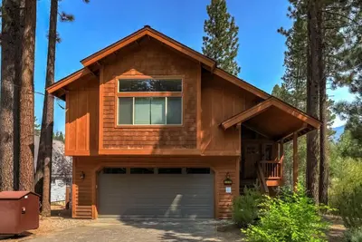 a house with a garage in the woods at Sierra Solace - Forest & Seasonal River Out Back in South Lake Tahoe