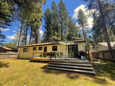 a small yellow house with a porch and a deck at Bear Claw Trails - Dogs - Awesome Yard - Fire Pit in Lake Tahoe Airport