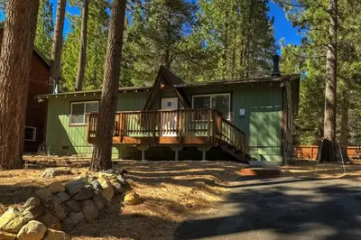 a green house with a deck in the woods at Bear Cub Cabin - Pets - Hot tub - Arcade Game in Mevers