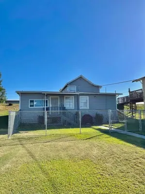 a house behind a chain link fence in a yard at Waterfront Home w 40x16 Berth in Bethel Island