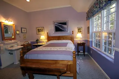 a bedroom with a bed and a sink and two windows at McCaffrey House Bed and Breakfast Inn in Twain Harte