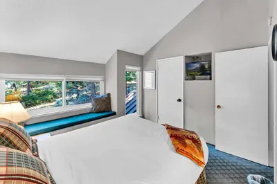 a bedroom with a bed and a couch and two windows at Carnelian Bay 2BR + Loft Near Beach & Trails in Carnelian Bay