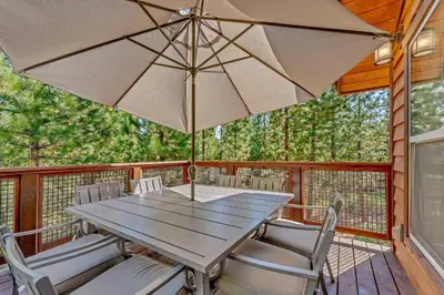 a table and chairs on a deck with an umbrella at Charming Tahoe Cabin with Private Beach Access in Tahoe City
