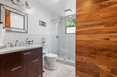 a bathroom with a toilet and a shower with a wooden door at Peaceful Creekside Buddha Retreat in Groveland