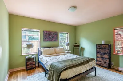 a bedroom with green walls and a bed and windows at Cozy 2BR Home Near UNR with Large Deck & Parking in Reno