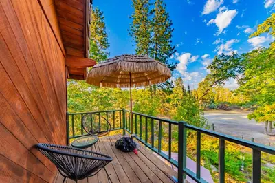 a balcony with a chair and an umbrella at Sunset Summit Villa 2 min from Bass Lake in Bass Lake