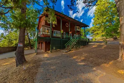a red house with a porch and a tree at Sunset Summit Villa 2 min from Bass Lake in Bass Lake