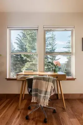 a desk and a chair in a room with two windows at Alpenglow Aerie - StayLuxe Rubicon in Meeks Bay
