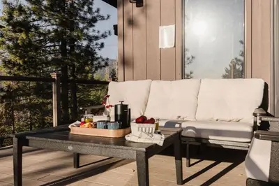 a couch sitting on a patio with a table at Alpenglow Aerie - StayLuxe Rubicon in Meeks Bay