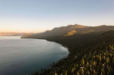 an aerial view of a lake with trees and mountains at Alpenglow Aerie - StayLuxe Rubicon in Meeks Bay