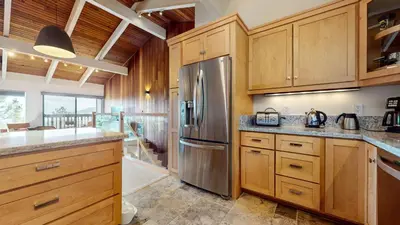 a kitchen with wooden cabinets and a stainless steel refrigerator at Mammoth Point #117 condo in Mammoth Lakes