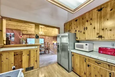 a kitchen with wooden cabinets and a stainless steel refrigerator at Cozy and central Tahoe cabin with private hot-tub outdoor fireplaces close to slopes in Ridgewood