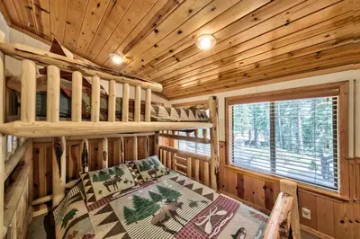 a log cabin bedroom with bunk beds and a window at Cozy and central Tahoe cabin with private hot-tub outdoor fireplaces close to slopes in Ridgewood