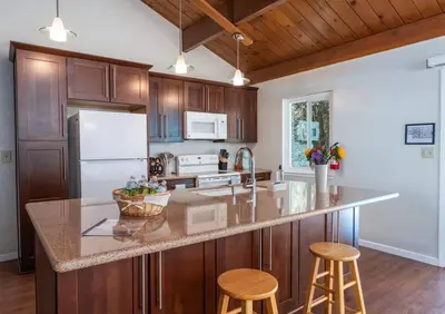 a kitchen with wooden cabinets and a large island with stools at Bald Bear Barracks in Mariposa
