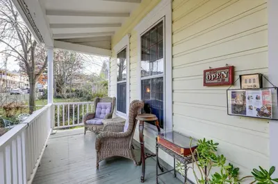 a porch with wicker chairs and a table and a window at Timeless Victorian Gem w Breathtaking Mountains in Sutter Creek