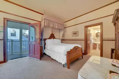 a bedroom with a large bed and a balcony at Romantic Victorian Getaway The Fox in Sutter Creek