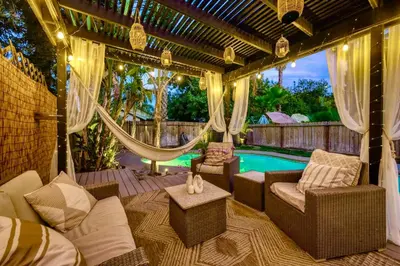 a patio with a hammock and a swimming pool at Chic Boho 3BR Home Near Woodward Park in Fresno