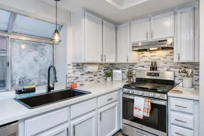 a white kitchen with a sink and a stove at Chic Boho 3BR Home Near Woodward Park in Fresno