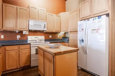 a kitchen with white appliances and wooden cabinets at Mammoth TwnHm hot tub walk to town in Mammoth Lakes