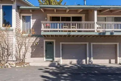 a house with a balcony and two garage doors at Mammoth TwnHm hot tub walk to town in Mammoth Lakes