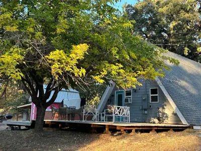 a house with a porch and a tree at Picturesque Yosemite A-Frame in Mariposa
