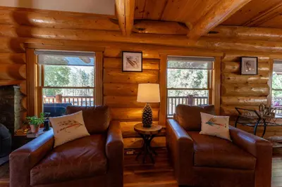 a living room with two leather couches in a log cabin at Peppermint Falls Ranch in Ponderosa