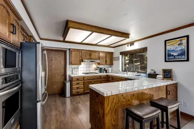a kitchen with a refrigerator and a counter with stools at Large Seasonal Rental South Lake Tahoe in South Lake Tahoe