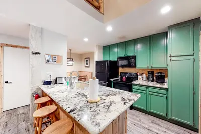 a kitchen with green cabinets and a marble counter top at Crestview 48 in Mammoth Lakes
