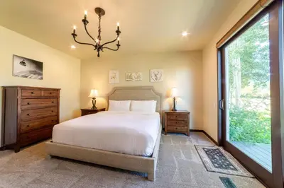 a bedroom with a bed and a window and a chandelier at Grand Townhome w/ Meadow Views; Private Garage in Mammoth Lakes