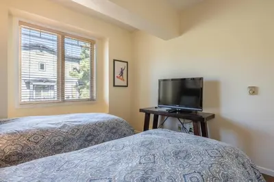 a bedroom with two beds and a flat screen tv at Mammoth Green #210 - Nearly Ski-in Ski-Out 2 Bedroom 2 Bath, Sleeps 6 on Golf Course in Mammoth Lakes