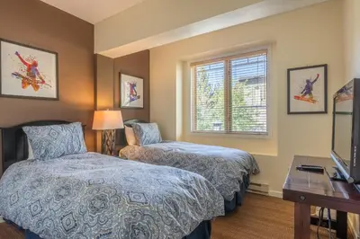 a bedroom with two beds and a desk and a television at Mammoth Green #210 - Nearly Ski-in Ski-Out 2 Bedroom 2 Bath, Sleeps 6 on Golf Course in Mammoth Lakes