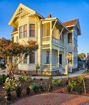 a yellow house with a balcony on a street at The JD Hyde Historic Inn in Visalia