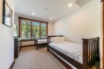 a bedroom with a bed and a dresser and a window at Iron Horse Lodge South 408 by East West Hospitality in Truckee