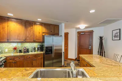 a kitchen with wooden cabinets and a stainless steel refrigerator at Iron Horse Lodge South 408 by East West Hospitality in Truckee