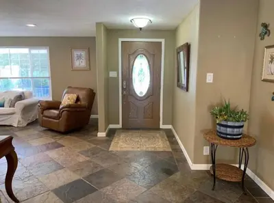 a living room with a brown door and a chair at Midtown Old Southwest Home With Pool! in Reno