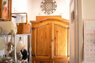 a wooden cabinet in a kitchen with a clock on the wall at 1 BR Orchard Cottage - Gateway to Two National Parks! in Visalia