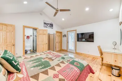 a bedroom with a large bed and a tv at Cottage Like Suite with Private Hot Tub in Bass Lake