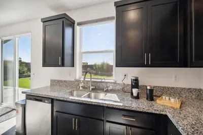 a kitchen with black cabinets and a sink at Spacious 3BR Home with Charming Backyard home in Folsom