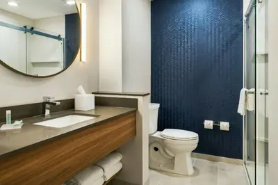a bathroom with a toilet and a sink and a mirror at Fairfield Inn & Suites Hanford in Hanford